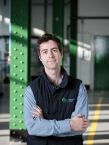 Man stands in blue gilet with arms crossed